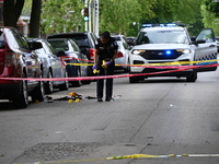 A crime scene investigator is placing evidence markers at the crime scene to show where a recovered firearm, articles of clothing, and other...