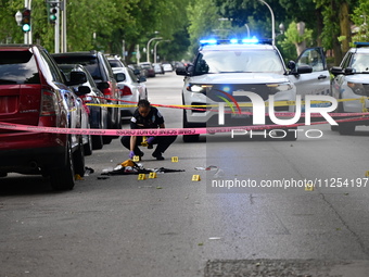 A crime scene investigator is placing evidence markers at the crime scene to show where a recovered firearm, articles of clothing, and other...