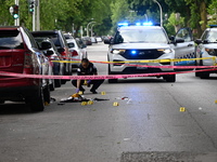 A crime scene investigator is placing evidence markers at the crime scene to show where a recovered firearm, articles of clothing, and other...