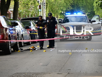 Crime scene investigators are placing evidence markers at the crime scene to show where a recovered firearm, articles of clothing, and other...