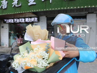 A courier is delivering flowers at a florist in Funing county, Yancheng city, East China's Jiangsu province, on May 20, 2024. (