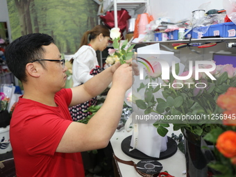 An employee is packing bouquets according to an order at a flower shop in Funing county, Yancheng city, East China's Jiangsu province, in Ya...