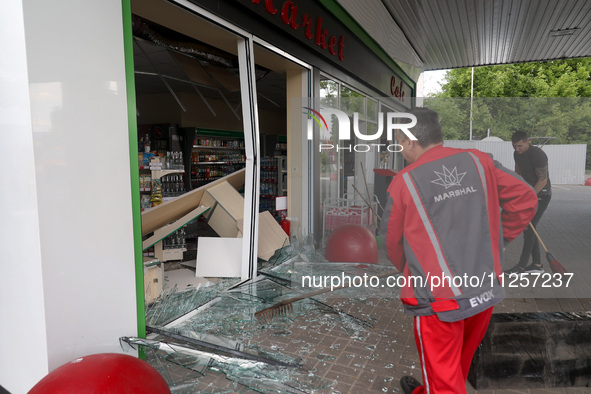 Workers are sweeping away glass shards at a petrol station damaged by Russian shelling in Kharkiv, Ukraine, on May 19, 2024. NO USE RUSSIA....