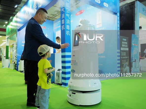 Visitors are experiencing an ''intelligent disinfection robot'' at the 32nd China International Health Industry Expo in Beijing, China, on M...