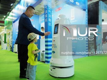 Visitors are experiencing an ''intelligent disinfection robot'' at the 32nd China International Health Industry Expo in Beijing, China, on M...