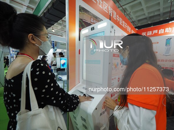 Visitors are experiencing a ''smart TCM self-service terminal'' system at the 32nd China International Health Industry Expo in Beijing, Chin...