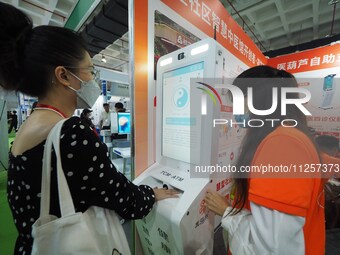 Visitors are experiencing a ''smart TCM self-service terminal'' system at the 32nd China International Health Industry Expo in Beijing, Chin...