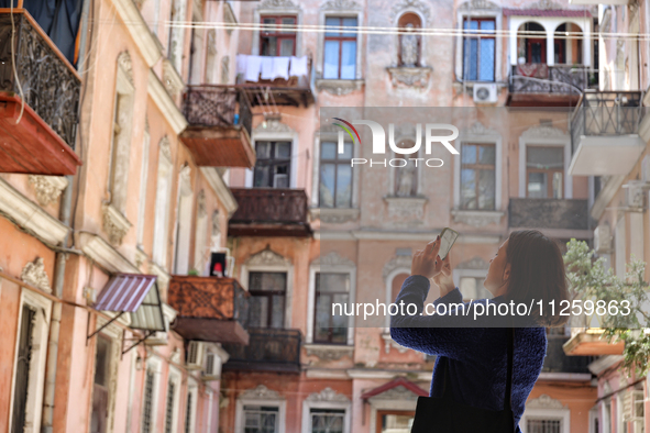 A woman is taking pictures of a courtyard in the historic city center in Odesa, Ukraine, on May 20, 2024. NO USE RUSSIA. NO USE BELARUS. 