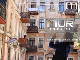 A woman is taking pictures of a courtyard in the historic city center in Odesa, Ukraine, on May 20, 2024. NO USE RUSSIA. NO USE BELARUS. (