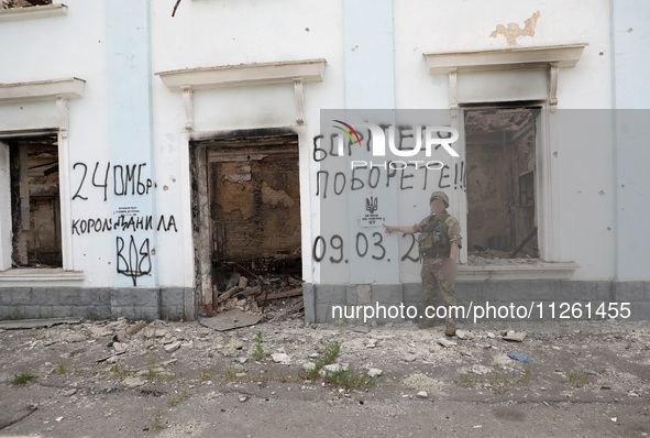 A serviceman is pointing at Ukraine's coat of arms and the phrase ''This Land Is Under Protection of ZSU (Ukrainian abbreviation of Ukraine'...