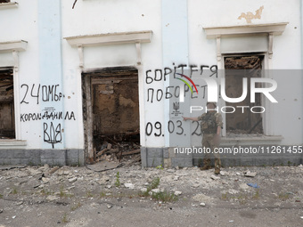 A serviceman is pointing at Ukraine's coat of arms and the phrase ''This Land Is Under Protection of ZSU (Ukrainian abbreviation of Ukraine'...