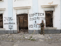 A serviceman is pointing at Ukraine's coat of arms and the phrase ''This Land Is Under Protection of ZSU (Ukrainian abbreviation of Ukraine'...