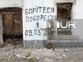 A serviceman is pointing at Ukraine's coat of arms and the phrase ''This Land Is Under Protection of ZSU (Ukrainian abbreviation of Ukraine'...