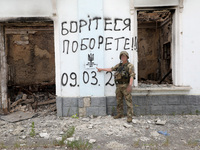 A serviceman is pointing at Ukraine's coat of arms and the phrase ''This Land Is Under Protection of ZSU (Ukrainian abbreviation of Ukraine'...