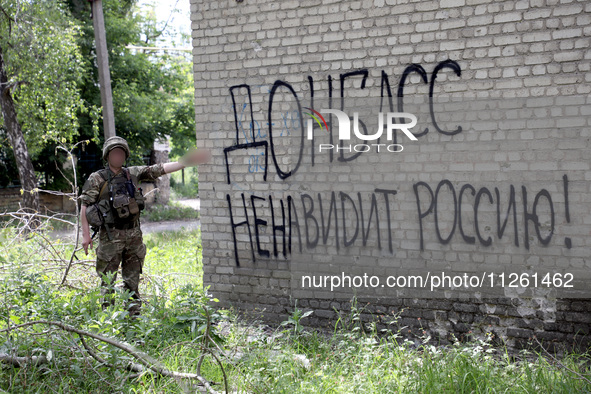 A soldier is pointing at the phrase in Russian ''Donbass Hates Russia!'' on the wall of a building in Chasiv Yar, Donetsk region, eastern Uk...