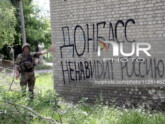 A soldier is pointing at the phrase in Russian ''Donbass Hates Russia!'' on the wall of a building in Chasiv Yar, Donetsk region, eastern Uk...