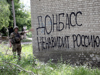 A soldier is pointing at the phrase in Russian ''Donbass Hates Russia!'' on the wall of a building in Chasiv Yar, Donetsk region, eastern Uk...