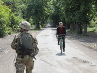 A serviceman is walking past an elderly man riding a bicycle along a street in Chasiv Yar, Donetsk region, eastern Ukraine, on May 18, 2024....