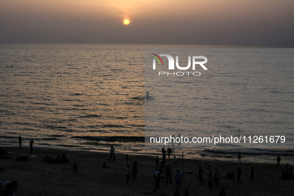 Palestinians are walking amidst tents housing internally displaced people, along the coastline in Deir el-Balah in the central Gaza Strip, o...