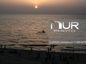 Palestinians are walking amidst tents housing internally displaced people, along the coastline in Deir el-Balah in the central Gaza Strip, o...