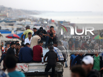 Palestinians are walking amidst tents housing internally displaced people, along the coastline in Deir el-Balah in the central Gaza Strip, o...