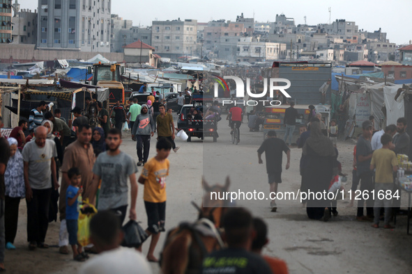 Palestinians are walking amidst tents housing internally displaced people, along the coastline in Deir el-Balah in the central Gaza Strip, o...