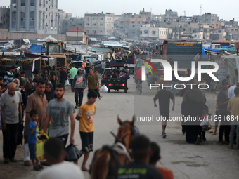 Palestinians are walking amidst tents housing internally displaced people, along the coastline in Deir el-Balah in the central Gaza Strip, o...