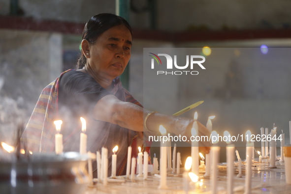 A Buddhist woman is lighting a candle at a temple on the occasion of the Buddha Purnima festival, which marks the birth of Gautam Buddha, in...