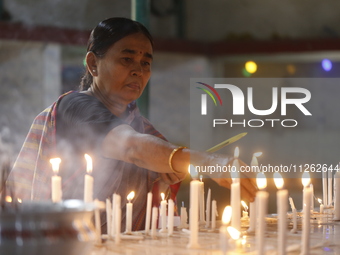 A Buddhist woman is lighting a candle at a temple on the occasion of the Buddha Purnima festival, which marks the birth of Gautam Buddha, in...