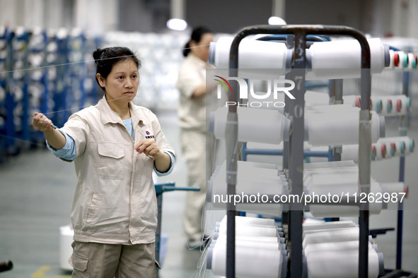 A worker is producing textile chemical fiber products on a production line in Fuzhou, China, on May 22, 2024. 