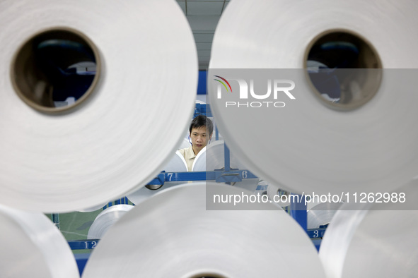 A worker is producing textile chemical fiber products on a production line in Fuzhou, China, on May 22, 2024. 