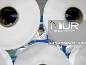 A worker is producing textile chemical fiber products on a production line in Fuzhou, China, on May 22, 2024. (