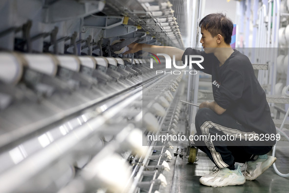 A worker is producing textile chemical fiber products on a production line in Fuzhou, China, on May 22, 2024. 