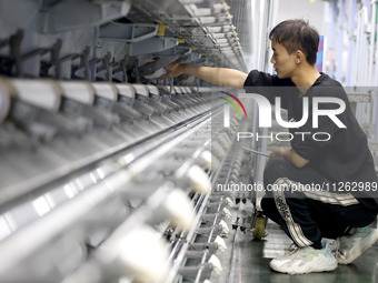 A worker is producing textile chemical fiber products on a production line in Fuzhou, China, on May 22, 2024. (