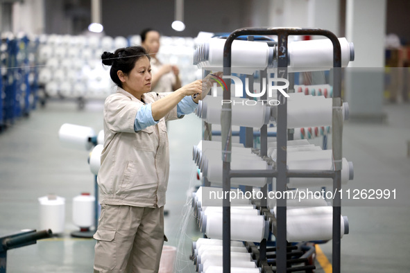 A worker is producing textile chemical fiber products on a production line in Fuzhou, China, on May 22, 2024. 