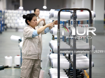 A worker is producing textile chemical fiber products on a production line in Fuzhou, China, on May 22, 2024. (