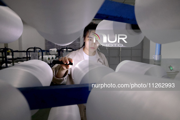 A worker is producing textile chemical fiber products on a production line in Fuzhou, China, on May 22, 2024. 