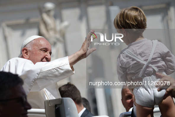 Pope Francis is waving to a child at the end of his weekly general audience in St. Peter's Square, at the Vatican, on May 22, 2024. 