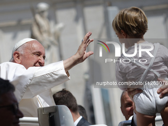 Pope Francis is waving to a child at the end of his weekly general audience in St. Peter's Square, at the Vatican, on May 22, 2024. (