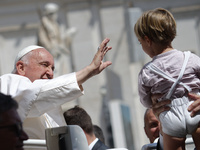 Pope Francis is waving to a child at the end of his weekly general audience in St. Peter's Square, at the Vatican, on May 22, 2024. (