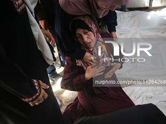 A displaced Palestinian mother is showering her child amid a heat wave inside a tent at a temporary camp in Deir el-Balah in the central Gaz...