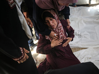 A displaced Palestinian mother is showering her child amid a heat wave inside a tent at a temporary camp in Deir el-Balah in the central Gaz...