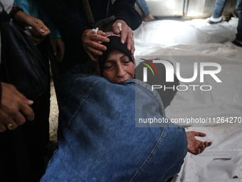 A displaced Palestinian mother is showering her child amid a heat wave inside a tent at a temporary camp in Deir el-Balah in the central Gaz...