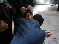 A displaced Palestinian mother is showering her child amid a heat wave inside a tent at a temporary camp in Deir el-Balah in the central Gaz...