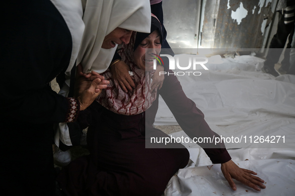 A displaced Palestinian mother is showering her child amid a heat wave inside a tent at a temporary camp in Deir el-Balah in the central Gaz...