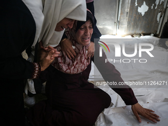 A displaced Palestinian mother is showering her child amid a heat wave inside a tent at a temporary camp in Deir el-Balah in the central Gaz...