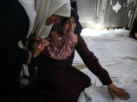 A displaced Palestinian mother is showering her child amid a heat wave inside a tent at a temporary camp in Deir el-Balah in the central Gaz...