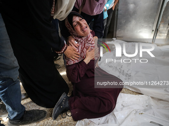 A displaced Palestinian mother is showering her child amid a heat wave inside a tent at a temporary camp in Deir el-Balah in the central Gaz...