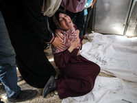 A displaced Palestinian mother is showering her child amid a heat wave inside a tent at a temporary camp in Deir el-Balah in the central Gaz...