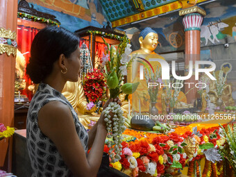 A lady is offering a lotus flower to an idol of Lord Buddha at a monastery on the occasion of Buddha Purnima in Kolkata, India, on May 23, 2...